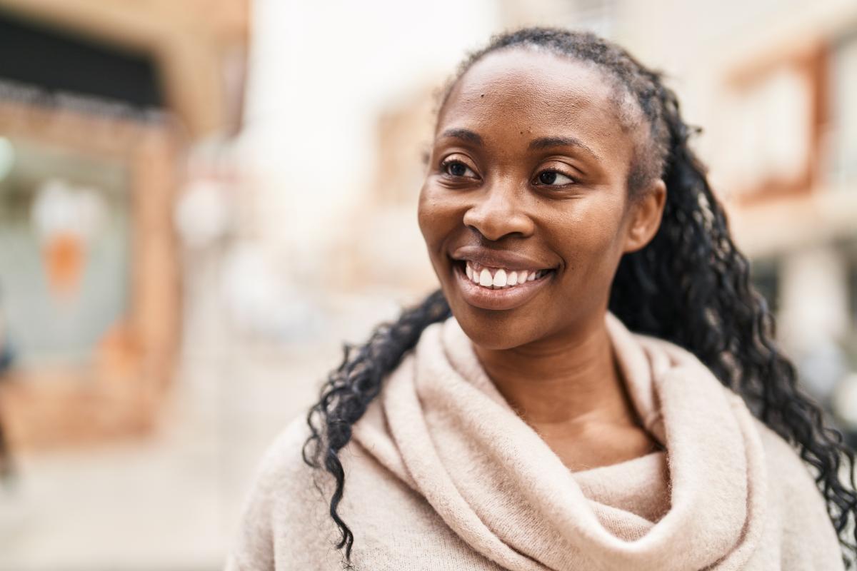 a woman smiles at the camera wearing a cream sweater while setting sober goals