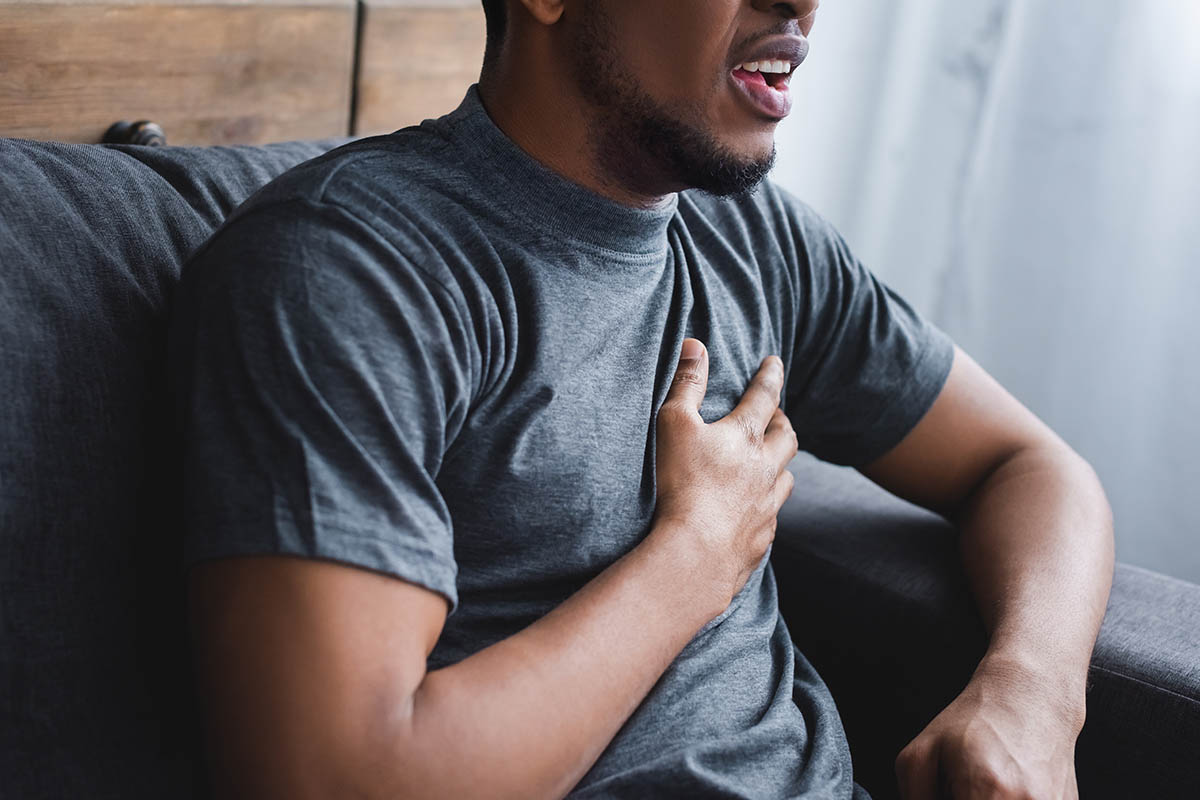 a person grasps their chest as they experience symptoms of panic attack