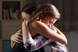 two people console each other in an embrace after finding a loved one showing symptoms of heroin abuse