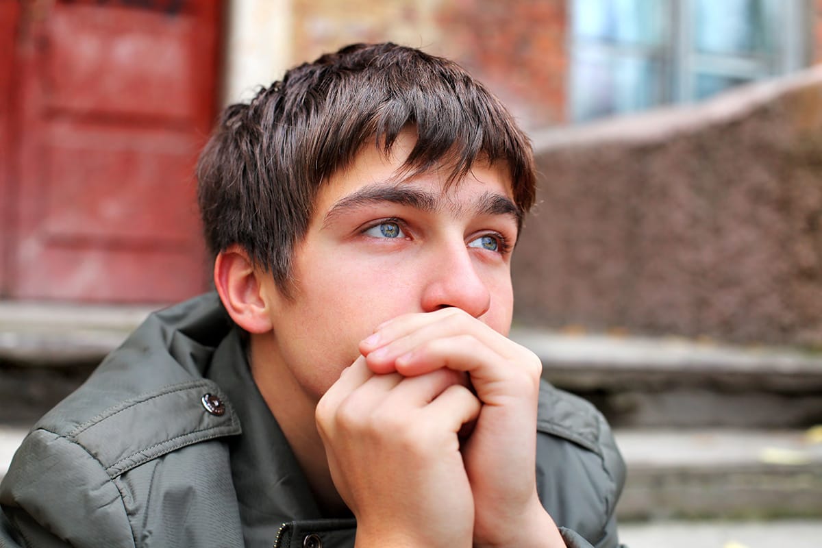 a person with dark brown short hair puts their mouth on their hands while experiencing depression in addiction recovery