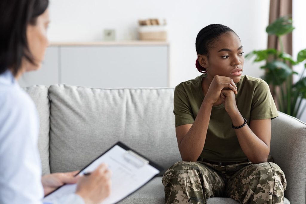 a veteran in fatigues talks to a therapist in a recovery program for veterans