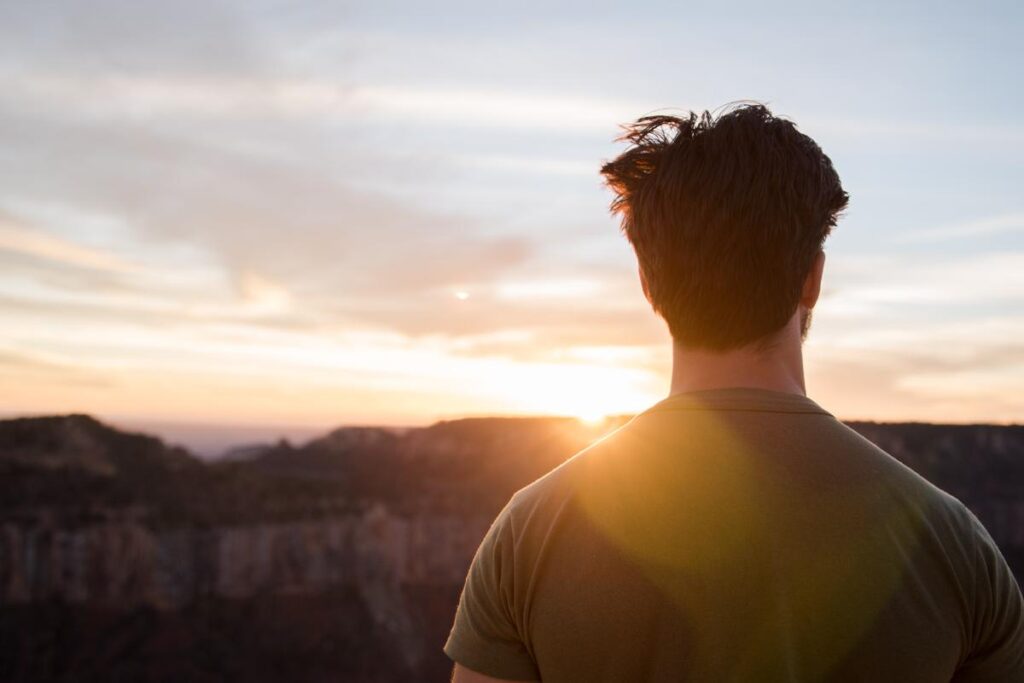 a person from behind as they look over a beautiful sunrise to signify life after rehab