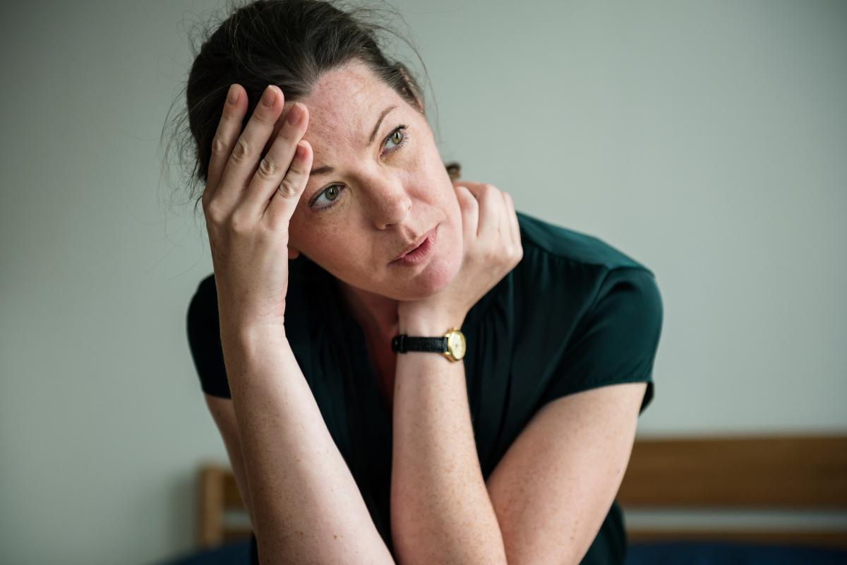 a person wonders what are co-occurring disorders while holding their neck and head and sitting against a wall