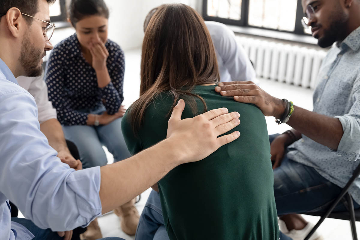 a group of people comfort someone in a medical detox center