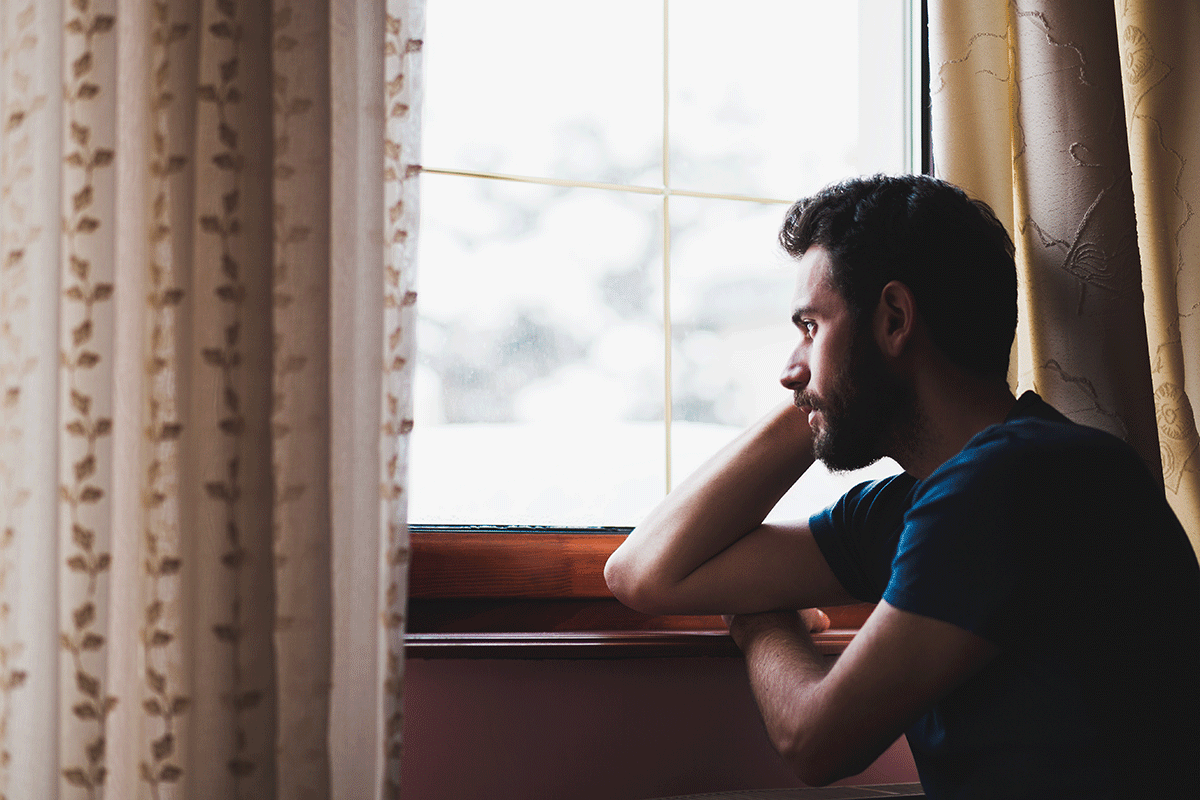 a person looks out a window while dealing with addiction and mental health conditions