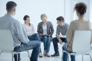 a group of people sit in chairs in a circle in an opioid rehab program