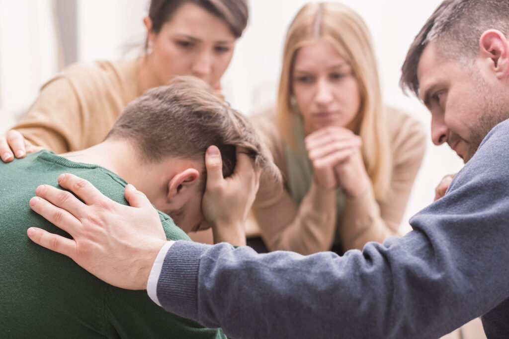 a group of people comfort a person during staging an intervention