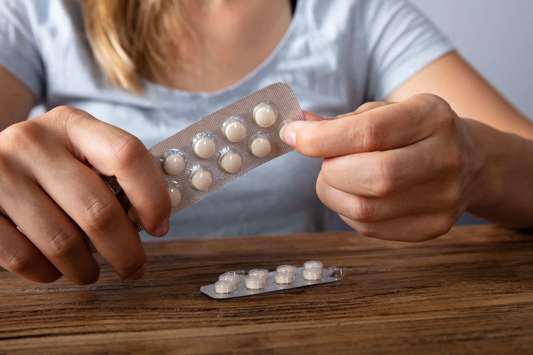 a person punches out a pack of pills to show opiate abuse