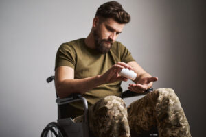 a veteran in a wheelchair empties out a pill bottle into their hand to show veterans and drug abuse