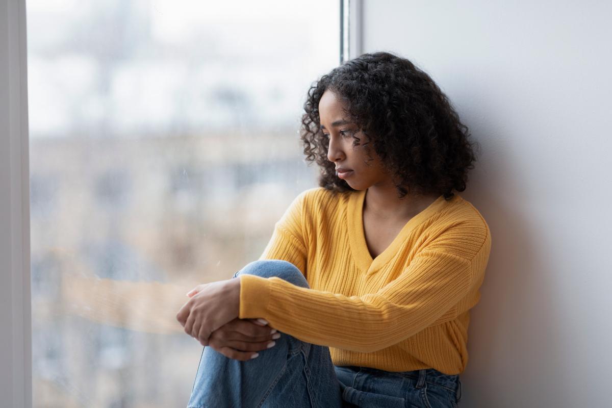 a person with long hair looks out a window showing signs of depression in women