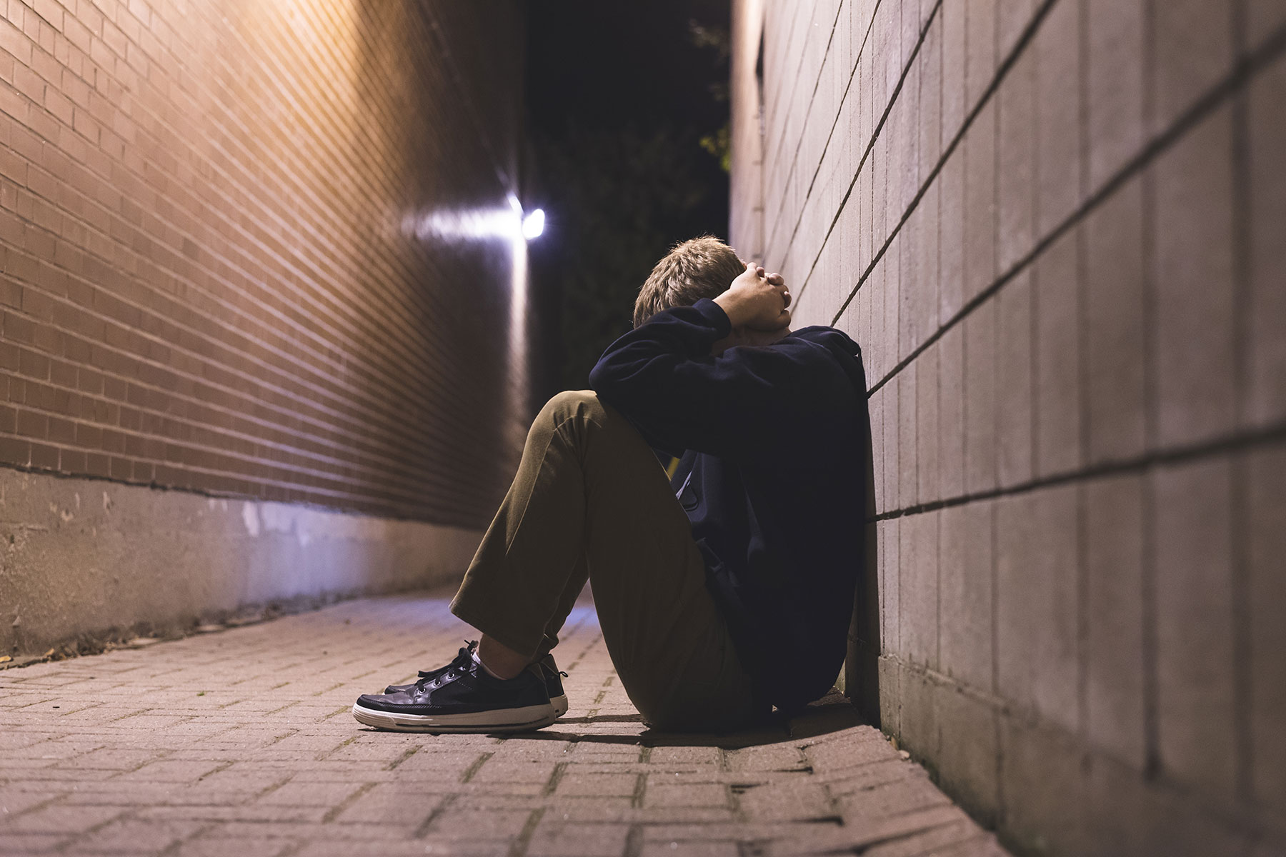 a person experiences xanax abuse and sits against a wall with their head in their lap