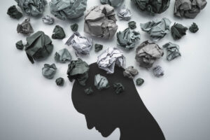 a shape of a profile of a person with crumbled paper coming out of the head to show anxiety and addiction
