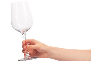 someone holds out a wine glass to represent self-medicating with alcohol