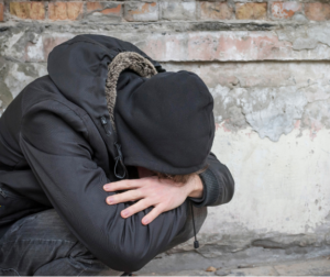 Man in hoodie leans down and cries while considering safe withdrawal from heroin